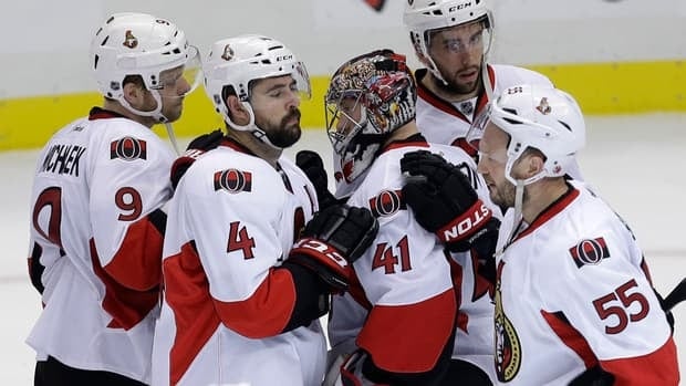 Senators goalie Craig Anderson is surrounded by teammates Milan Michalek (9), Chris Phillips (4), Sergei Gonchar (55) and Jared Cowen after being eliminated by the Penguins.