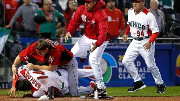 Canada's Jay Johnson, top left, and Mexico's Eduardo Arredondo fight during the ninth inning of a World Baseball Classic game, Saturday Phoenix, Ariz. (AP Photo/Matt York)