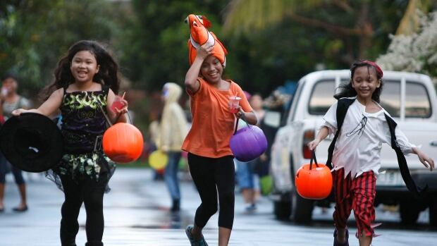Children make the rounds of the houses at a subdivision at the financial district of Makati city in the Philippines.
