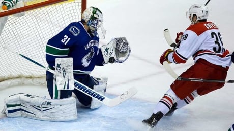 Vancouver Canucks goalie Eddie Lack, left, stops Carolina Hurricanes forward Patrick Dwyer during the second period in Vancouver on Monday. Eddie Lack, Hurricanes