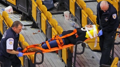 Emergency workers remove an injured woman from TD Garden after suffering injuries when a metal pole holding up protective netting behind one of the goals fell, after a Boston Bruins game on Thursday. 620-bruins-fans