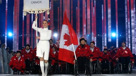 Canada's flag-bearer Sonja Gaudet, centre, leads the country's 54-athlete contingent into Fisht Stadium for the opening ceremony. Canada enters the Paralympics opening ceremony