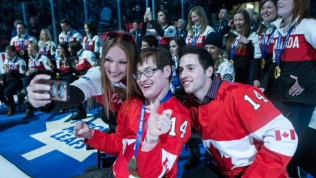 Heather Moyse (centre left) takes a selfie with Alexandre Bilodeau (right) and his brother Frederic as Canadian Olympic medalists are honoured before Toronto Maple Leafs take on Philadelphia Flyers in NHL hockey action in Toronto on Saturday March 8, 2014. Leafs, Olympians