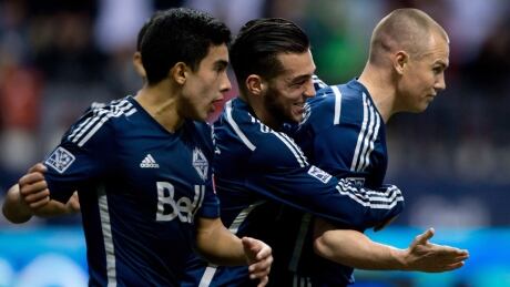 Vancouver Whitecaps' Sebastian Fernandez, from left to right, Russell Teibert and Kenny Miller celebrate Miller's penalty kick goal against the New York Red Bulls during the first half in Vancouver on Saturday. Miller, Whitecaps
