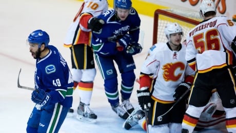 Vancouver Canucks' Darren Archibald, left, celebrates after scoring as Calgary Flames' Ladislav Smid, second right, and Tyler Wotherspoon, right, stand in front of goalie Joni Ortio during the second period in Vancouver on Saturday. Canucks, Flames