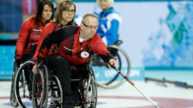 Canada's Dennis Thiessen throws a rock during wheelchair curling round-robin play at the Sochi Paralympics.