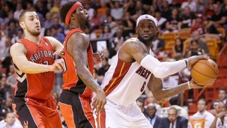 Miami Heat forward LeBron James looks for an open teammate past Toronto Raptors centreJonas Valanciunas, left, and forward John Salmons during the first half on Monday. LeBron James