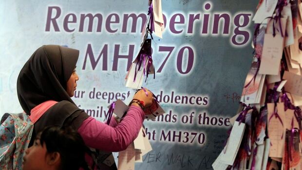 A woman ties a message card for passengers who were aboard missing Malaysia Airlines Flight MH370, at a shopping mall in Kuala Lumpur, Malaysia on Saturday.
