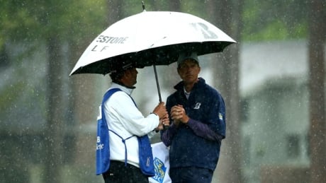 Matt Kuchar, right, and his caddie huddle under an umbrella during Friday's soggy second round at Harbour Town Golf Links. kuchar-matt-140418