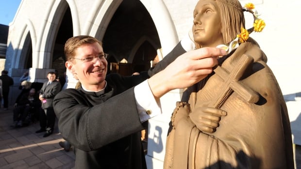 A clergy member places flowers on a statue of Saint Kateri Tekakwitha at Saint Kateri Tekakwitha Roman Catholic Church in Lagrangeville, N.Y., in 2012. Because of Canada's residential school history, many people assume today's Aboriginal Peoples want little to do with the church.