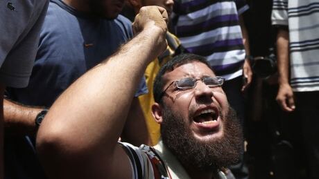 Palestinian mourner chants slogans on the grave of a member of the al-Batsh family who were killed in an Israeli airstrike, during a funeral procession in Gaza City on Sunday, July 13, 2014. The strike hit the home of a cousin of Gaza police chief Taysir al-Batsh and damaged a nearby mosque as evening prayers ended Saturday, killing at least 18 people, wounding 50 and leaving some people believed to be trapped under the rubble, said Palestinian Health Ministry official Ashraf al-Kidra. Mideast Israel Palestinians