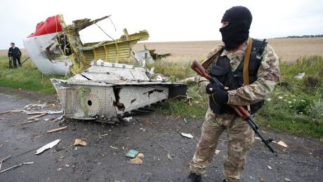 A pro-Russian separatist stands at the crash site of Malaysia Airlines flight MH17, near the settlement of Grabovo in the Donetsk region, July 18, 2014. Monitors from the Organisation for Security and Cooperation in Europe (OSCE) were not able to secure an access corridor on Friday to the site where a Malaysian airliner crashed in eastern Ukraine, the OSCE's chairman said. UKRAINE-CRISIS/AIRPLANE-OSCE