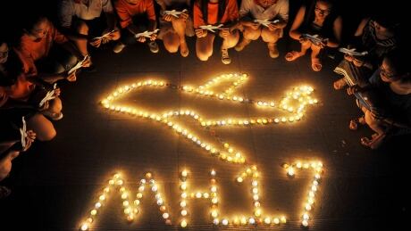 College students gather around candles forming the shape of an airplane at a university in Yangzhou, Jiangsu province on July 19, 2014. Malaysian Airlines MH17 Candlelight vigil