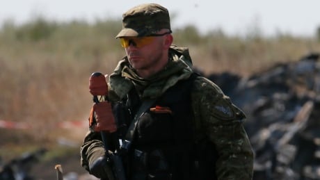 An armed pro-Russian separatist guards a crash site of the Malaysia Airlines Flight MH17 near the village of Hrabove (Grabovo), Donetsk region July 24, 2014. REUTERS/Maxim Zmeyev (UKRAINE - Tags: TRANSPORT DISASTER) - RTR400EF Malaysia Airlines Flight MH17 Ukraine crisis