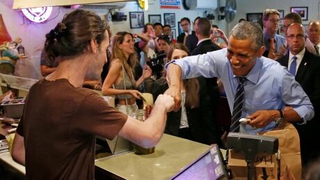 U.S. President Barack Obama fist bumps the cashier after paying for his order at Franklin Barbecue in Austin, Texas July 10, 2014. USA-OBAMA/
