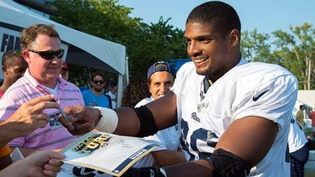 Rams rookie defensive lineman Michael Sam (96) signs autographs following practice at Rams Park in St. Louis on Tuesday. sam-michael-140729