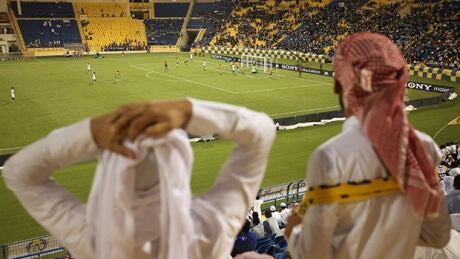 DOHA, QATAR - OCTOBER 23: Fans wearing traditional local dress react to play during the Gharafa vs. Kharaitiyat Qatar Stars League football match at Al Gharafa Stadium on October 23, 2011 in Doha, Qatar. Qatar will host the 2022 FIFA World Cup football competition and is slated to tackle a variety of infrastructure projects, including the construction of new stadiums. q-history