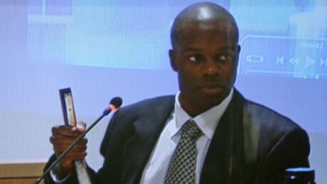 RCMP Const. Kwesi Millington is seen on a television holding up the stapler Polish immigrant Robert Dziekanski was holding the night he died, while testifying at the Braidwood inquiry. Taser Inquiry 20090302