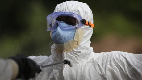 A burial team member wearing personal protective equipment (PPE), stands for decontamination spray at the U.S.-built cemetery for "safe burials" in Disco Hill, Liberia on Tuesday. Disco Hill/Liberia/Ebola