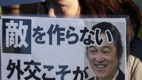 A woman cries as she holds a portrait of Japanese journalist Kenji Goto on a placard, during a rally against Japan's Prime Minister Shinzo Abe, in front of Abe's official residence in Tokyo, February 1, 2015. Islamic State militants said they had beheaded a second Japanese hostage, journalist Kenji Goto, prompting Prime Minister Shinzo Abe to vow to step up humanitarian aid to the group's opponents in the Middle East and help bring his killers to justice. The words on the placard are the part of 'Diplomacy not to make an enemy protects a Japanese'. REUTERS/Toru Hanai (JAPAN - Tags: POLITICS CRIME LAW CIVIL UNREST TPX IMAGES OF THE DAY) - RTR4NR6Y MIDEAST-CRISIS/JAPAN-HOSTAGE