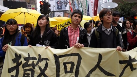 Student leader Alex Chow, center, carries a banner with other students during a democracy march to Central, demanding for universal suffrage in Hong Kong Sunday, Feb. 1, 2015. The march is the first large-scale demonstration since the Occupy Central protest ended last year as the government started a second round of public consultation on democratic reform. The banner reads: "Withdraw." (AP Photo/Kin Cheung) Hong Kong Democracy Protest
