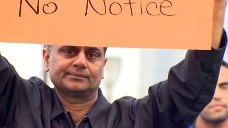 A trucker holds a sign at Saturday's rally in Surrey's Holland Park. Hundreds of truckers were protesting after being denied access to the port under Port Metro Vancouver's new licensing system for trucks. Port Metro Vancouver truckers rally