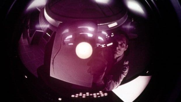 An astronaut looks at his reflection in a camera in a scene from the film '2001: A Space Odyssey', 1968.