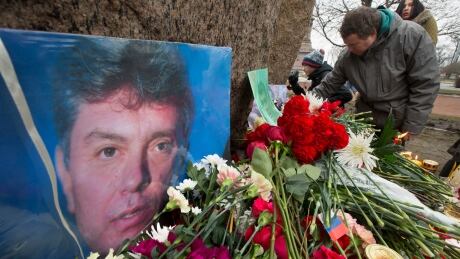 People lay flowers in memory of Boris Nemtsov, seen at left, at the monument of political prisoners 'Solovetsky Stone' in central St. Petersburg, Russia, on Saturday. Russia Opposition Leader Killed