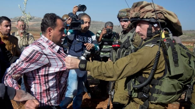 A confrontation between an Israeli soldier and a Palestinian during a demonstration against Israeli settlements in the village of Turmus Aya near the West Bank city of Ramallah, Wednesday, Dec. 10, 2014.