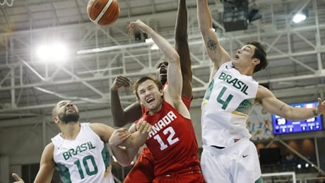 Canada's Brady Heslip, centre, and teammate Anthony Bennett, back, go up for the ball against Brazil's Carlos Nascimento, left, and Ricardo Fischer during the second quarter of the men's basketball gold-medal game. basketball-canada-brazil-620