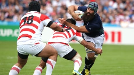 Scotland's Josh Strauss attempts to elude a pair of Japanese tacklers at the Rugby World Cup in Gloucester, England. Scotland scored five second-half tries to roll to a 45-10 win. Scotland-Japan-Rugby