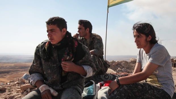 Members of the Kurdish People's Protection Units, or YPG, stand guard near a check point in the outskirts of the destroyed Syrian town of Kobani in this June 20 photo. A Canadian man arrested in Iraq reportedly had volunteered with the YPG.