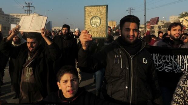 Men hold Koran holy book as they demonstrate outside the offices of the Al-Qaeda-linked Islamic State of Iraq and the Levant (ISIS) demanding that they stop fighting with the rebels on January 6, 2014 in the northern Syrian city of Aleppo.