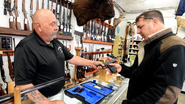 Bill Karnok, left, of Grandpa's Pawn Shop in Longmont, Colo., shows a gun to a customer on Tuesday, Jan. 5, 2016 - the day President Barack Obama unveiled his plans to tighten control and enforcement of firearms in the U.S. (Cliff Grassmick/Daily Camera via AP)