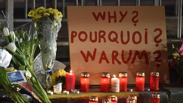 A sign reads "Why?" in English, French and Flemish behind candles and flowers near the Maelbeek metro station, in Brussels on Wednesday evening, March 23, 2016. Bombs exploded Tuesday at Brussels airport and one of the city's metro stations, killing and wounding scores of people, as a European capital was again locked down amid heightened security threats. (AP Photo/Martin Meissner)