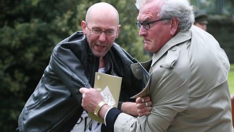 Canadian Ambassador to Ireland Kevin Vickers, right, wrestles with a protester during a State ceremony to remember the British soldiers who died during the Easter Rising at Grangegorman Military Cemetery, Dublin Thursday May 26, 2016. Vickers helped subdue a demonstrator who began chanting "insult" at the service commemorating more than 100 British soldiers killed trying to suppress the Easter Rising a century ago. Kevin Vickers protester