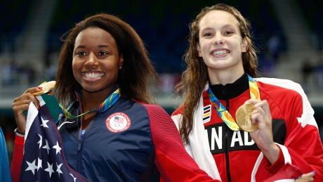 RIO DE JANEIRO, BRAZIL - AUGUST 11: Gold medalist Simone Manuel of the United States (L) and gold medalist Penny Oleksiak of Canada celebrate during the medal ceremony for the Women's 100m Freestyle Final on Day 6 of the Rio 2016 Olympic Games at the Olympic Aquatics Stadium on August 11, 2016 in Rio de Janeiro, Brazil. (Clive Rose/Getty) rio highlights day 6 aug 11 2016 simone manuel penny oleksiak