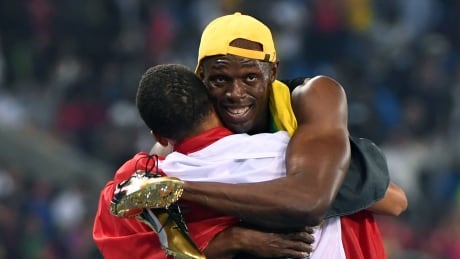 Jamaica's Usain Bolt (R) hugs third placed Canada's Andre De Grasse as he celebrates winning the Men's 100m Final during the athletics event at the Rio 2016 Olympic Games at the Olympic Stadium in Rio de Janeiro on August 14, 2016. / AFP / OLIVIER MORIN (Photo credit should read (Olivier Morin/AFP/Getty) Name * Rio Olympics Day 9 Aug 14 2016 highlights de grasse bolt hug
