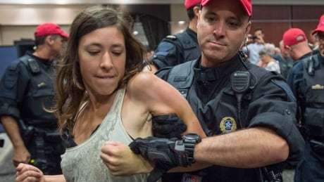 A demonstrator is taken away by a police officer after disrupting the National Energy Board public hearing into the proposed $15.7-billion Energy East pipeline project proposed by TransCanada on Aug. 29, 2016 in Montreal. Energy East Hearings