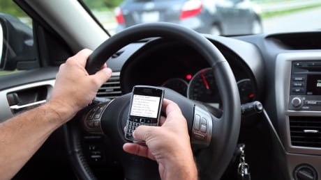 A driver looks at his mobile phone while driving Friday, August 17, 2012 in Montreal. Canadians send nearly 10 million text messages an hour or 227 million per day on their cellphones. The Canadian Wireless Telecommunications Association wants pedestrians to pay attention when texting, and does not want people driving and texting. Cyberfile Texting Dangers