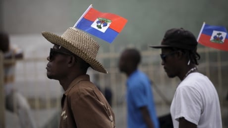 Two protesters carriying Haitian flags on his heads march during a demonstration against the electoral process in Port-au-Prince, Haiti, January 22, 2016. Haiti postponed a U.S.-backed presidential election as violent protests erupted on Friday after the opposition candidate vowed to boycott the vote over alleged fraud. HAITI-ELECTION/PROTEST