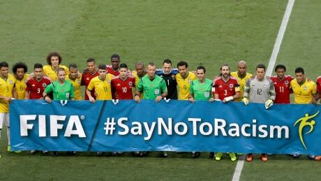 Players and referees gather behind a banner against racism prior to the World Cup quarterfinal soccer match between Brazil and Colombia. Brazil Soccer WCup Brazil Colombia