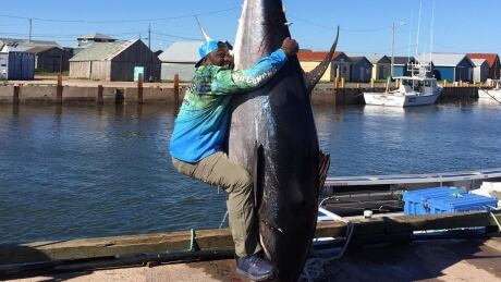 Warren Sapp, listed as 6-foot-2 and 300 pounds during his playing days with the Tampa Bay Buccaneers and Oakland Raiders, hugs a tuna on the wharf at North Lake, P.E.I., last week. Warren Sapp