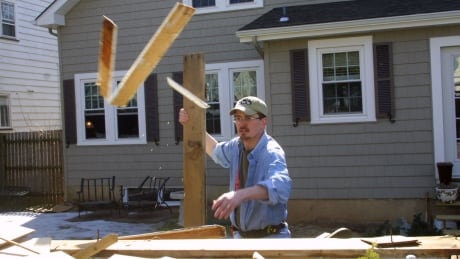 Gerard Leary tosses some old lumber into a dumpster in front of the home he is renovating in North Plainfield, New Jersey, on Saturday, February 28, 2004. Leary knocked $700 off the monthly mortgage payment of his 80-year-old Colonial-style home when he refinanced three weeks ago with an adjustable-rate mortgage. Photographer: John Rizzo/Bloomberg News construction renovation