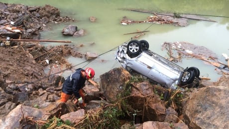 A rescue worker is seen Thursday next to an overturned car at the site of a landslide caused by heavy rains brought by Typhoon Megi, in Sucun Village, Lishui, Zhejiang province. ASIA-STORM/CHINA