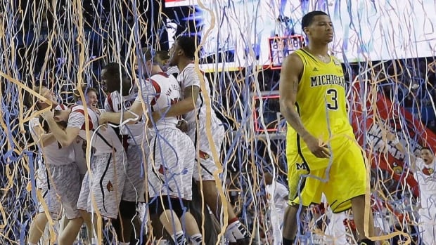 Michigan guard Trey Burke (3) walks off the court as Louisville celebrates their win after the second half of the NCAA Final Four tournament college basketball championship game Monday, April 8, 2013, in Atlanta. Louisville won 82-76. (AP Photo/Charlie Neibergall)
