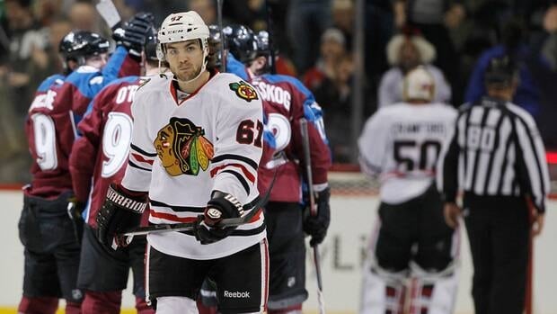 Blackhawks' Michael Frolik skates back to the bench as Avalanche players celebrate a goal.
