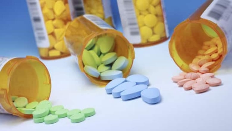 Different-coloured pills spill out of three bottles.