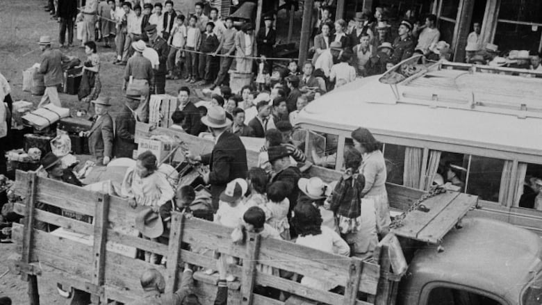People on the back of trucks in a black and white photo.
