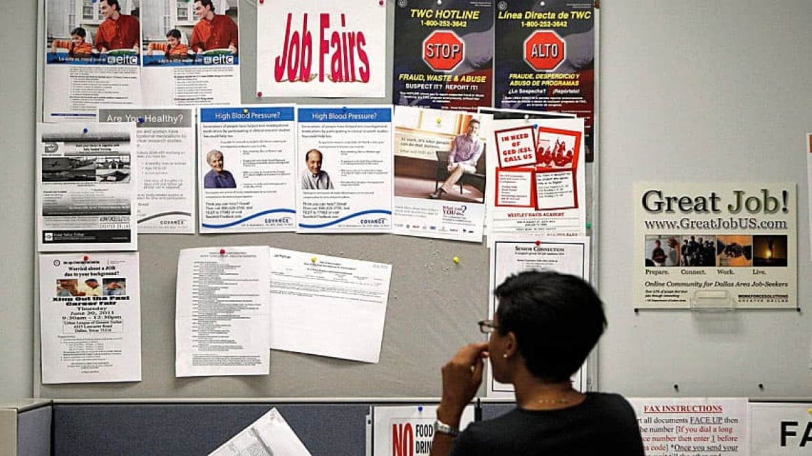 A person looks at a notice board advertising a job fair.